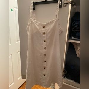 White mini dress with buttons down the front and a tie back with opening